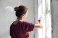 Woman in a white apron paints a window in a house interior renovation Royalty Free Stock Photo