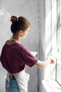 Woman in a white apron paints a window in a house interior renovation Royalty Free Stock Photo