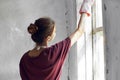 Woman in a white apron paints a window in a house interior renovation Royalty Free Stock Photo