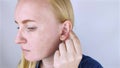 A woman on a white background shows her ear. The macro video shows the curl of the auricle, which has a tubercle. Plastic surgery