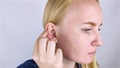 A woman on a white background shows her ear. The macro video shows the curl of the auricle, which has a tubercle. Plastic surgery