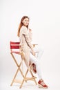 Woman on a white background sits on a high chair, fashion, beauty, style, full-length