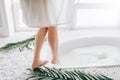 Woman in white bathrobe dips legs into the bath Royalty Free Stock Photo