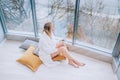 Woman in a white bathrobe enjoying sea view next to big window with cup of coffee. Panoramic window. Floor covering, Vacation in a Royalty Free Stock Photo