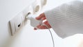 Woman in white bathrobe inserting plug into outlet at home with hand closeup Royalty Free Stock Photo
