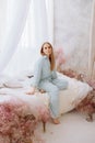 A woman in a white bathrobe sits on a bed with flowers Royalty Free Stock Photo