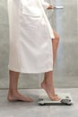 Woman in white bathrobe standing on weigher Royalty Free Stock Photo