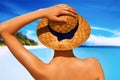 Woman in white bikini resting on the beach in straw hat