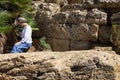 Woman in a white blouse and a turban sits on antique ruins near palm tree. The Valle dei Templi, Agrigento, Sicily, Italy Royalty Free Stock Photo