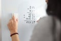 Woman on white board adds math numbers