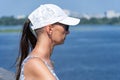 Woman in white cap and sunglasses thoughtfully looks at picturesque river. Royalty Free Stock Photo