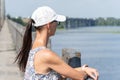 Woman in white cap and sunglasses thoughtfully looks at picturesque river. Royalty Free Stock Photo