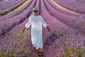 Woman with white clothes and hat walking in lavender violet field flowers. Female enjoy scenic travel destination. Outdoor leisure Royalty Free Stock Photo