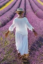 Woman with white clothes and hat walking in lavender violet field flowers. Female enjoy scenic travel destination. Outdoor leisure