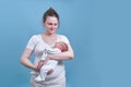 A woman in white clothes is holding a newborn baby on a blue background. Mother with a child boy in her arms, studio shot Royalty Free Stock Photo