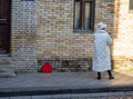 A woman in a white coat and white hat. The woman is standing with her back. Suitcase on the sidewalk. Waiting for a meeting Royalty Free Stock Photo