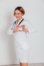 A woman doctor in a white coat with a phonendoscope, a stethoscope on a white background, shows a heart Royalty Free Stock Photo