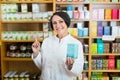 Woman in white coat promoting food additive goods in carton in drugstore Royalty Free Stock Photo