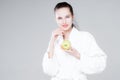 Woman in white coat smiling holding an apple in one hand and leaning against her face with the other Royalty Free Stock Photo