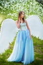 woman in a white corset and blue lush dress with large white angel wings behind her back Royalty Free Stock Photo