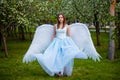 woman in a white corset and blue lush dress with large white angel wings behind her back Royalty Free Stock Photo