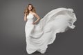 Woman in White Dress. Beauty Bride Model in Wedding Gown Flying on Wind over Gray Background. Bridal Fashion Clothing Royalty Free Stock Photo