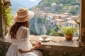 Woman in white dress enjoys coffee overlooking a cliffside Italian village