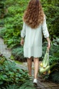 Woman in white dress going and carrying bags with different vegetables