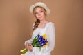 A woman in a white dress and hat holds a bouquet of tulips and irises. March 8. Women's Day. Women's holiday. Mom's holiday. Bouqu Royalty Free Stock Photo