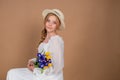 A woman in a white dress and hat holds a bouquet of tulips and irises. March 8. Women's Day. Women's holiday. Mom's holiday. Bouqu