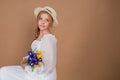 A woman in a white dress and hat holds a bouquet of tulips and irises. March 8. Women's Day.