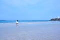 Woman in white dress with her long hair blowing in the wind, walking in a beach with white lighthouse on rocky platform in Jeju Is Royalty Free Stock Photo