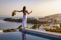 A woman in white dress at the pool enjoys the sunset behind the mediterranean sea Royalty Free Stock Photo