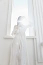 Woman in white dress rays sun window posing Royalty Free Stock Photo