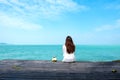 Woman on white dress sitting and looking at the sea and blue sky on wooden balcony with feeling relaxed Royalty Free Stock Photo