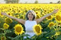 Woman in white dress standing with arms raised in a field of sunflowers in summer bloom Royalty Free Stock Photo