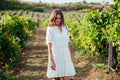 a woman in a white dress stands by a grape field road Royalty Free Stock Photo