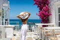 Woman in white dress stands in a typical whitewashed alley on a Greek island in the cyclades, Paros