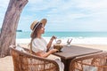 Woman in White Dress and Straw Hat Sitting on Table in Outdoor Beach Cafe Royalty Free Stock Photo