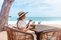 Woman in White Dress and Straw Hat Sitting on Table in Outdoor Beach Cafe Royalty Free Stock Photo