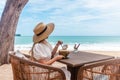 Woman in White Dress and Straw Hat Sitting on Table in Outdoor Beach Cafe Royalty Free Stock Photo