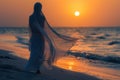 A woman in a white dress is walking on the beach at sunset Royalty Free Stock Photo