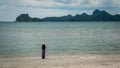 Woman in white fedora hat and sarong standing on the beach with islands in the background