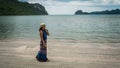 Woman in white fedora hat and sarong standing on the beach with islands in the background