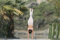 A woman in a white gymnastic jumpsuit is engaged in yoga on the background of water and a green mountain slope Royalty Free Stock Photo