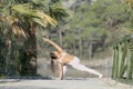 A woman in a white gymnastic jumpsuit is engaged in yoga on the background of water and a green mountain slope Royalty Free Stock Photo