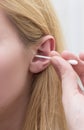 Woman with white hairs is cleaning her ears with white cotton bud. Royalty Free Stock Photo