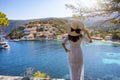 A woman with white hat enjoys the view to the village of Assos on the island of Kefalonia, Greece