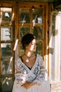 Woman in a white lace cape sits near an antique wooden door. Portrait Royalty Free Stock Photo