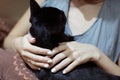 A woman with a white manicure strokes a black cat